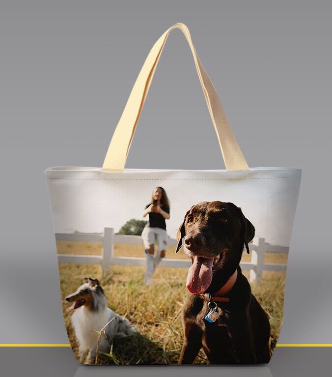 A all over print custom tote bag with a photo of a woman and two dogs is a thoughtful and unique gift. The bag is large and the photo is vibrant, making it a conversation starter.