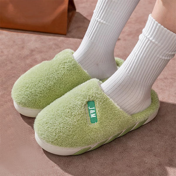 Green custom slippers worn with white socks on a brown surface