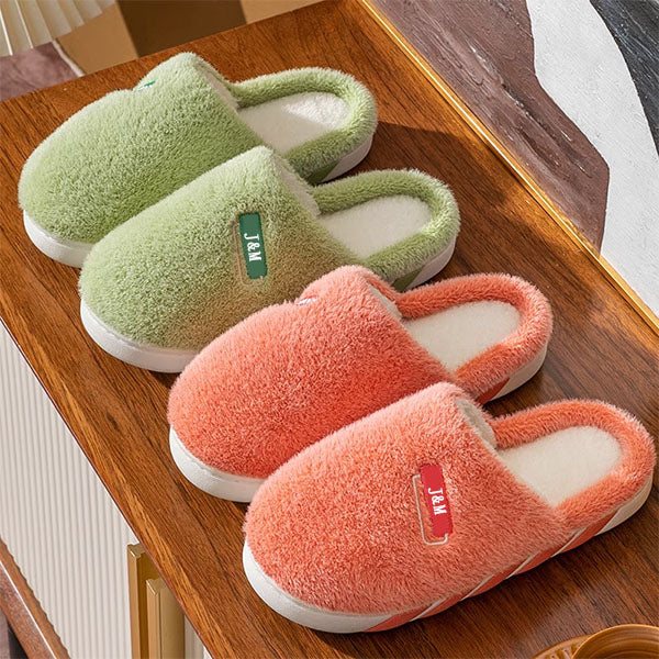 Personalized green and orange slippers on a wooden surface